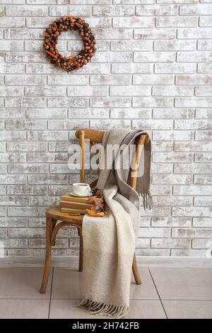 Belle couronne de glands sur un mur de briques claires et une tasse de café avec des livres sur la chaise dans la chambre Banque D'Images