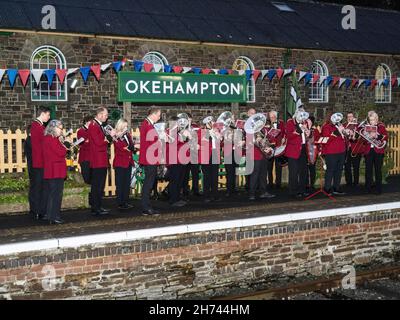 Samedi, 20 novembre, 2021 - le Hatherleigh Silver Band se produit à la gare d'Okehampton pour accueillir le premier train de la ligne Dartmoor.Un service régulier de transport de passagers à Exeter a été inauguré après un écart de près de 50 ans.Pour renouveler la voie, 11 milles de nouvelle voie ont été posés, avec 24,000 traverses en béton, et 29,000 tonnes de balast.Le rétablissement du service régulier améliorera les liens pour les navetteurs et fournira un terminal pour les visiteurs qui pourront explorer le parc national de Dartmoor.Il stimulera les entreprises locales, le secteur du tourisme et offrira un meilleur accès au travail et à l'éducation pour les locaux. Banque D'Images