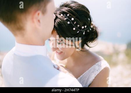 Le marié épouse la mariée et embrasse le front, la mariée sourit, gros plan Banque D'Images