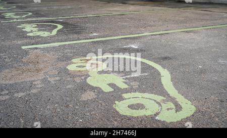 Panneau de véhicule électrique peint sur une route asphaltée indiquant un point de charge dans un parking Banque D'Images