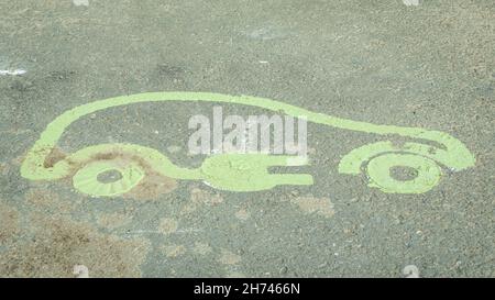 Panneau de véhicule électrique peint sur une route asphaltée indiquant un point de charge dans un parking Banque D'Images