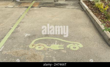 Panneau de véhicule électrique peint sur une route asphaltée indiquant un point de charge dans un parking Banque D'Images