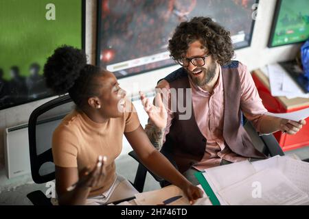 Les jeunes collègues ont une belle conversation tout en travaillant ensemble dans une atmosphère agréable au bureau Banque D'Images