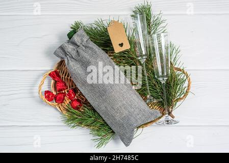 Sac cadeau de Noël et verre de vin sur plateau en osier. Banque D'Images