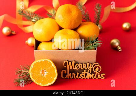 Mandarines dans une boîte cadeau sur fond de décorations de noël dorées.Mandarines de clémentine fraîches et juteuses, fruits de l'hiver.Vue latérale Banque D'Images