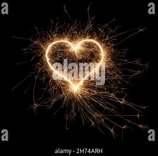golden bright sparkler coeur forme amour symbole en forme isolé sur fond noir foncé. silvester nouveau anniversaire mariage et célébration design pa Banque D'Images