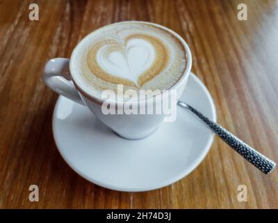 Tasse à café blanche avec latte en forme de cœur dans un café. Banque D'Images