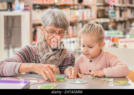 La petite-fille et la grand-mère ont mis en place un puzzle dans la bibliothèque Banque D'Images