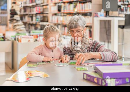 La petite-fille et la grand-mère ont mis en place un puzzle dans la bibliothèque Banque D'Images