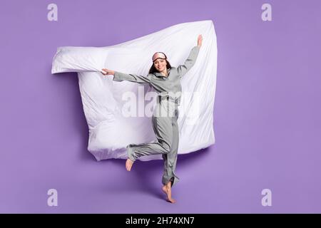 Photo de la taille du corps de fille joueur saut en gardant l'oreiller dans gris vêtements de nuit isolé pastel couleur violet arrière-plan Banque D'Images