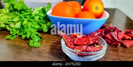 Quelques légumes, tomates Coriander et piments rouges entiers, pour faire du chutney et de la sauce sur une table en bois Banque D'Images