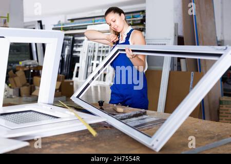 Femme utilisant un tournevis sur l'assemblage du cadre de fenêtre en usine Banque D'Images