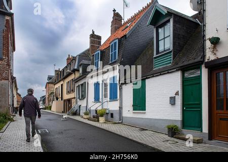 Rue du village avec un touriste, un chien et de vieilles maisons dans la ville de Saint Valéry-sur-somme en France Banque D'Images