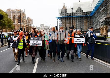 Londres, Royaume-Uni.20 novembre 2021.Des militants sont vus marcher le long de Westminster avec des armes verrouillées pendant la manifestation.Les militants d'Isolate Britain ont défilé en solidarité avec les neuf activistes qui ont été emprisonnés pour avoir obtenu une injonction en participant à un blocus à la jonction 25 de la M25 le 8 octobre pour appeler le gouvernement à financer l'isolation du logement social d'ici 2025 et de toutes les maisonsEn Grande-Bretagne d'ici 2030.La marche a commencé aux cours royales de justice à 12:00 et les militants sont prêts à provoquer la désobéissance civile dans la ville.Crédit : SOPA Images Limited/Alamy Live News Banque D'Images