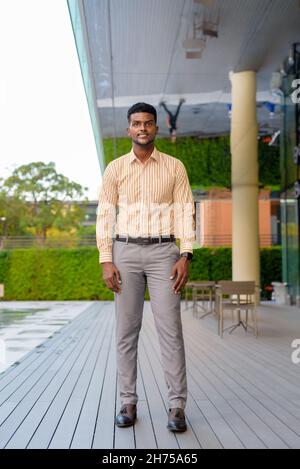 Portrait en longueur d'un jeune homme d'affaires africain beau dans la ville verticale Banque D'Images