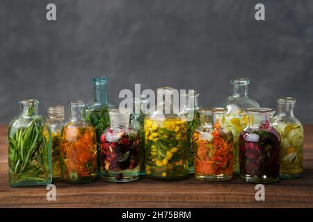 Bouteilles d'huile essentielle ou infusion d'herbes médicinales et de baies - romarin, calendula, tansy, thuja, thym,bergamote, camomille.Plantes de guérison, Banque D'Images