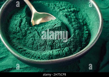 Poudre d'algues de spiruline bleu-vert sur une cuillère dans un bol, gros plan Banque D'Images