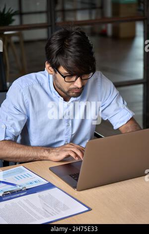 Jeune homme d'affaires indien de l'est utilisant un ordinateur portable travaillant au bureau. Banque D'Images