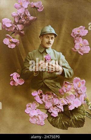 Un portrait de la première Guerre mondiale d'un soldat français en uniforme et casque tenant une fleur tout en pensant à sa chérie.Tiré d'une carte postale datée de 1917. Banque D'Images