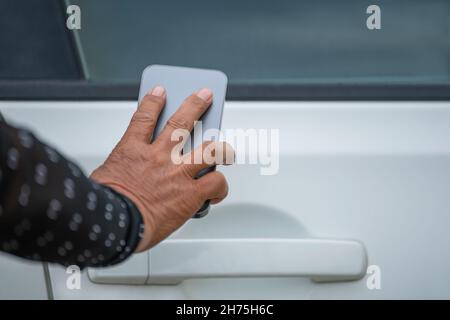 Une femme ouvre sa voiture avec son téléphone cellulaire Banque D'Images