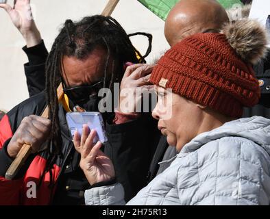 Kenosha, Wisconsin, États-Unis.19 novembre 2021.JUSTIN BLAKE avec des lunettes de soleil, l'oncle de Jacob Blake a l'espoir parfois avec un poing levé comme il regarde un smartphone pour des nouvelles de verdict vendredi 19 novembre 2021 à l'extérieur de Kenosha, Wisconsin, palais de justice du comté comme verdicts ont été annoncés acquittant Kyle Rittenhouse.L'ÉVÊQUE Tavis GRANT II de l'opération Rainbow PUSH Coalition est à côté de lui.La femme de Blake est la femme qui porte la veste légère.(Image de crédit : © Mark Hertzberg/ZUMA Press Wire) Banque D'Images