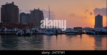 Port de plaisance de Porto Arabia dans la perle Doha Qatar coucher de soleil avec Yachts en premier plan, bâtiments et nuages dans le ciel en arrière-plan Banque D'Images