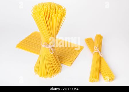 Ensemble de paquets de spaghetti bruts, liés avec du fil, sur fond blanc.Cuisine italienne. Banque D'Images