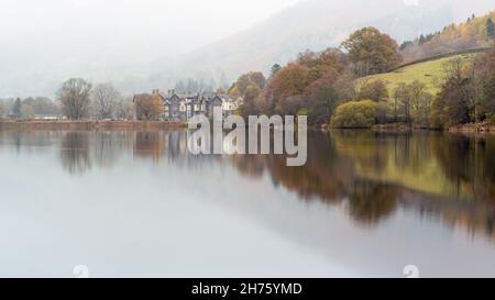 Un matin d'automne à Grasmere dans le parc national du Lake District avec l'hôtel Daffodil reflété dans les eaux calmes du lac. Banque D'Images