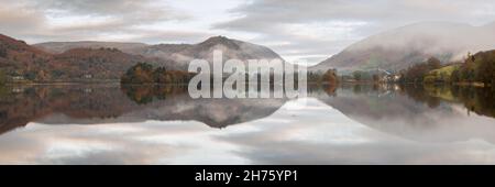 Le village de Grasmere et les coquillages environnants sont parfaitement reflétés dans les eaux calmes du lac, le matin d'automne, tandis que la brume se dissipe lentement. Banque D'Images