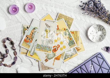 Les cartes Tarot se répandent face vers le haut sur une surface tricotée blanche avec boule de cristal, lavande, bougies et accessoires.Vue de dessus.Minsk, Bélarus, 11.10.2021 Banque D'Images