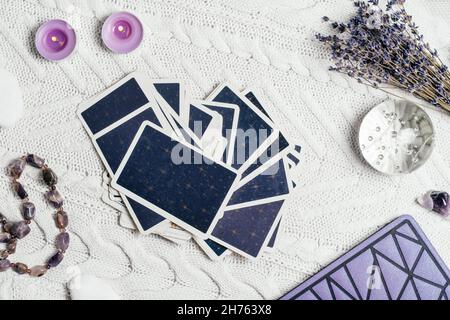 Les cartes Tarot se répandent face vers le bas sur une surface tricotée blanche avec boule de cristal, lavande, bougies et accessoires.Vue de dessus.Minsk, Bélarus, 11.10.2021 Banque D'Images