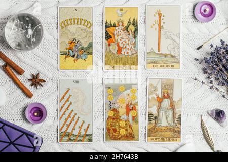 Les cartes Tarot se répandent face vers le haut sur une surface tricotée blanche avec boule de cristal, lavande, bougies et accessoires.Vue de dessus.Minsk, Bélarus, 11.10.2021 Banque D'Images