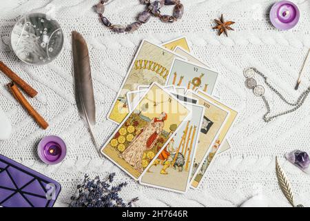 Les cartes Tarot se répandent face vers le haut sur une surface tricotée blanche avec boule de cristal, lavande, bougies et accessoires.Vue de dessus.Minsk, Bélarus, 11.10.2021 Banque D'Images