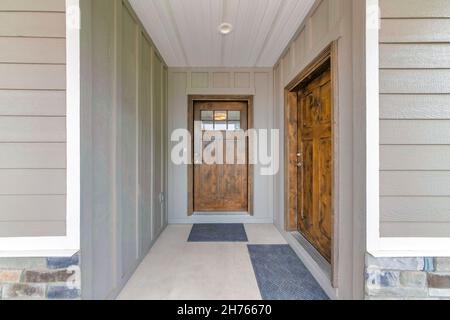 Deux portes avant en bois avec panneaux de verre et tapis de porte noirs Banque D'Images