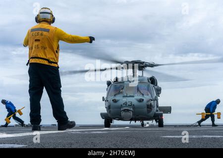 211117-N-FA490-1217 MER DE CHINE MÉRIDIONALE (NOV17, 2021) le compagnon de Boatswain de 2e classe Patrick Hix, d’Independence (Missouri), affecté au navire de combat littoral version Independence USS Jackson (LCS 6) dirige les marins d’un hélicoptère MH-60S affecté aux “caractères génériques” de l’Escadron de combat en mer d’hélicoptère (HSC) 23 sur le pont de vol, pendant les opérations d’acheminement.Jackson, qui fait partie de l'escadron Destroyer Seven, est en cours de déploiement rotatif dans la zone d'exploitation de la 7e flotte des États-Unis afin d'améliorer l'interopérabilité avec ses partenaires et de servir de force d'intervention en appui à une région Indo-Pacifique libre et ouverte.(É.-U. Banque D'Images