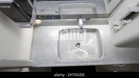 Lavabo en plastique dans la salle de bains de la cabine de toilette du porte-avions Boeing 737-800.Confort public et toilettes à bord d'un avion. Banque D'Images