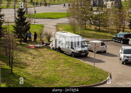 Un minibus avec les effets des migrants d'Asie centrale se trouve dans le parking et attend des compatriotes dans la rue au printemps. Banque D'Images