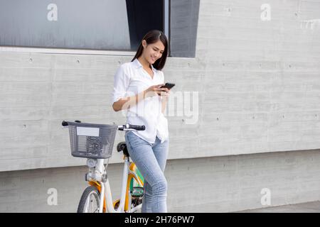Jeune femme utilisant un smartphone tout en faisant du vélo Banque D'Images