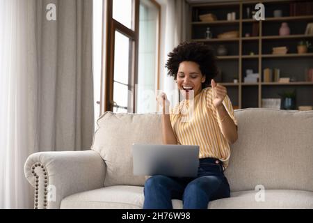 Jeune femme noire joyeuse et excitée utilisant un ordinateur portable Banque D'Images