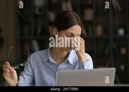Une femme d'affaires fatiguée prend le pont de nez de massage de lunettes Banque D'Images