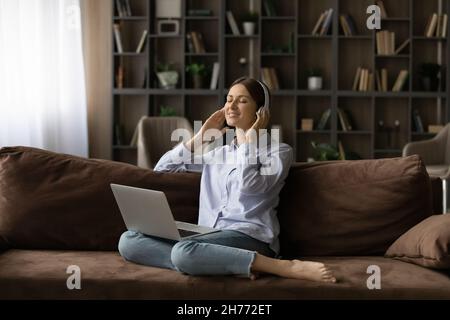 Une femme écoute de la musique via un casque à l'aide de services de diffusion sur un ordinateur portable Banque D'Images