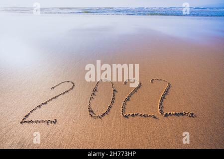 2022 panneau écrit à la main sur la plage de sable.Paysage marin abstrait dans les couleurs or et bleu, espace de copie.Concept du nouvel an 2022 Banque D'Images