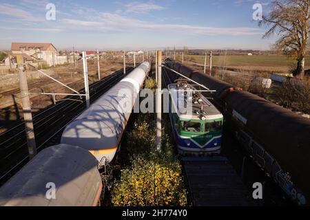 Buftea, Roumanie - 20 novembre 2021 : locomotive de trains de marchandises et wagons de pétrole dans une gare. Banque D'Images