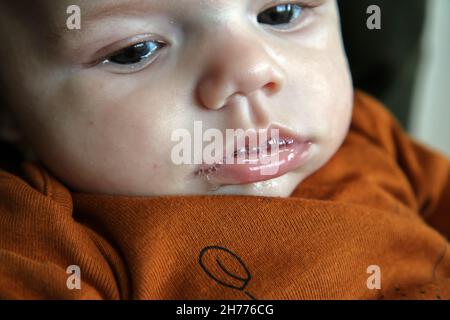 Le détail du bébé ayant de la mousse du castor sur sa bouche.Je ne regarde pas heureux et je l'absorbe dans les pensées. Banque D'Images