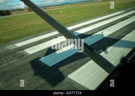 La vue de l'avion d'atterrissage avant le toucher de la piste avec le marquage de retenue visible.L'ombre du plan est également visible. Banque D'Images