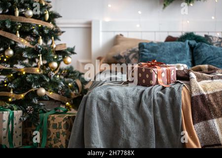 Intérieur d'une chambre confortable avec un sapin de Noël et une boîte cadeau sur le lit. Banque D'Images