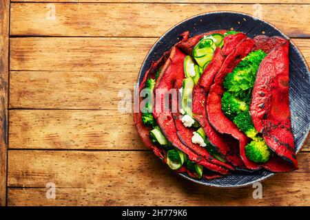 Crêpes aux betteraves farcies de légumes sur une table rustique en bois.Une alimentation saine.Espace pour le texte Banque D'Images