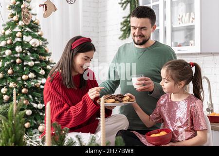 Bonne famille avec des biscuits de Noël et du lait dans la cuisine. Banque D'Images