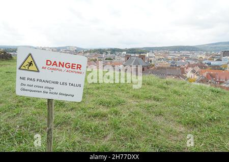 Panneau d'avertissement pour éviter le basculement, le retournement, en anglais, allemand et français attaché au bâton de bois situé sur la pente d'herbe à Belfort . Banque D'Images