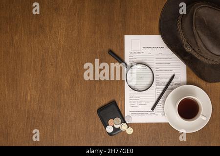 Formulaire de demande de visa sur une table en bois, vue de dessus, pose à plat, traitement des visas. Banque D'Images